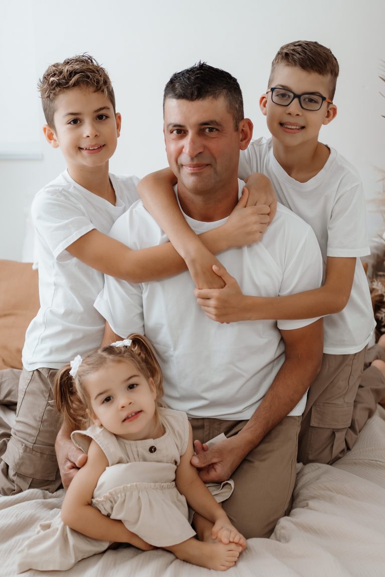 Vater sitzt mit seinen Kindern auf einem Bett bei einem Familienshooting – natürliche Familienfotografie in Singen und Waldshut-Tiengen